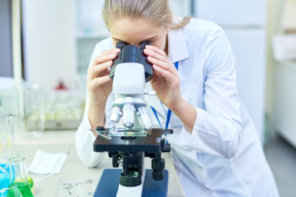 Serious,Experienced,Female,Scientist,Working,With,Modern,Microscope,While,Holding